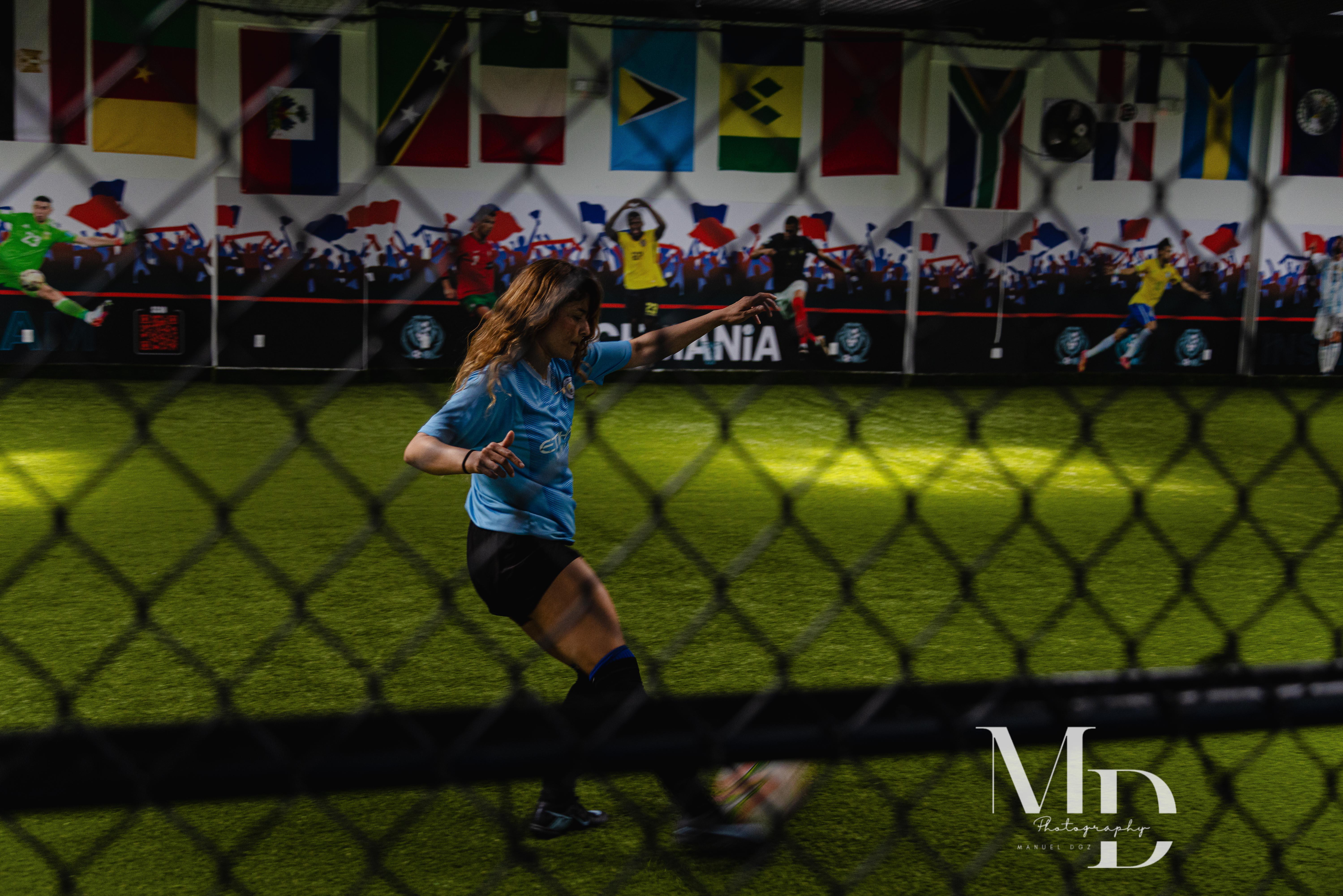 Player in a light blue jersey striking the ball on the turf