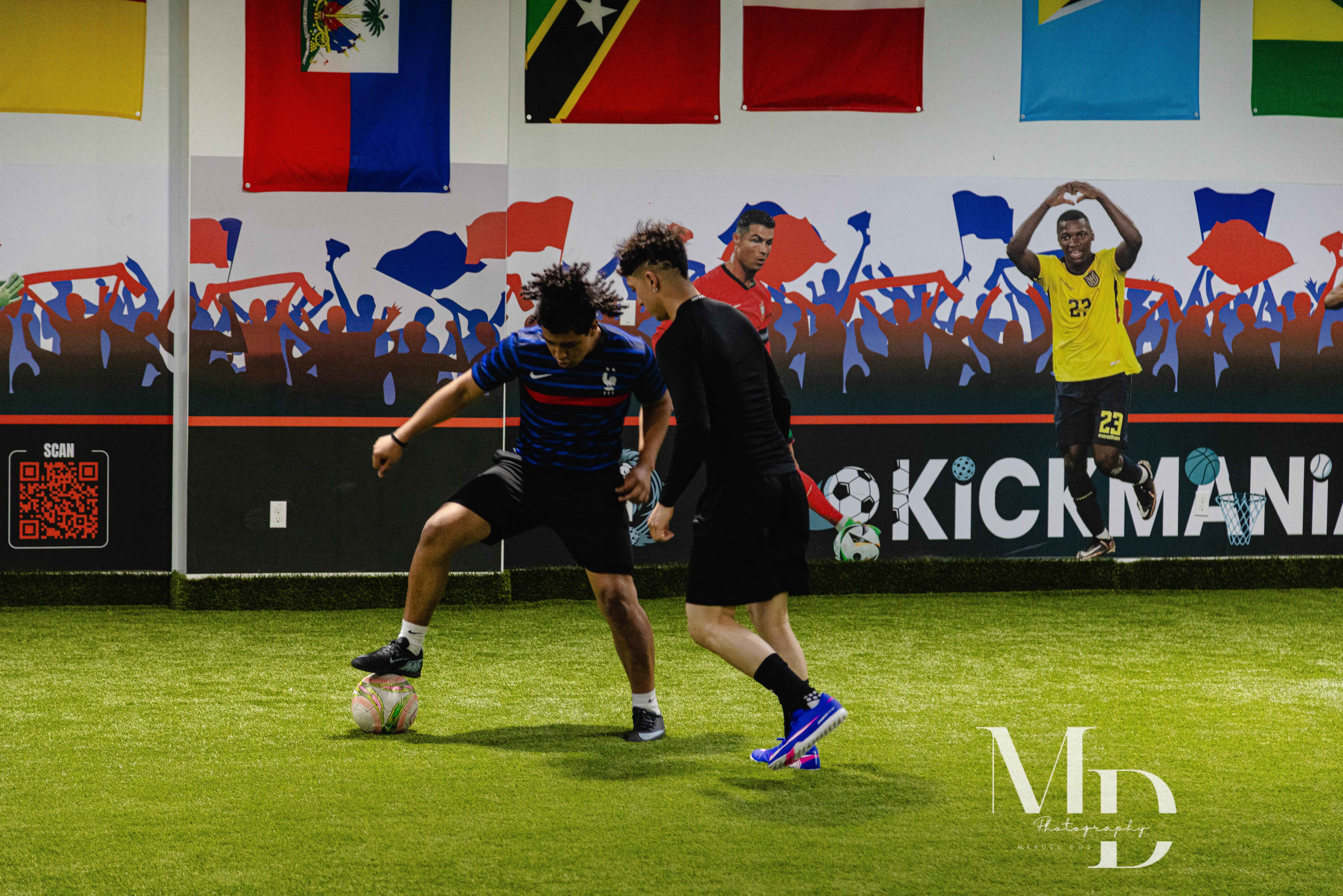 Two players battling for the ball in front of the player mural