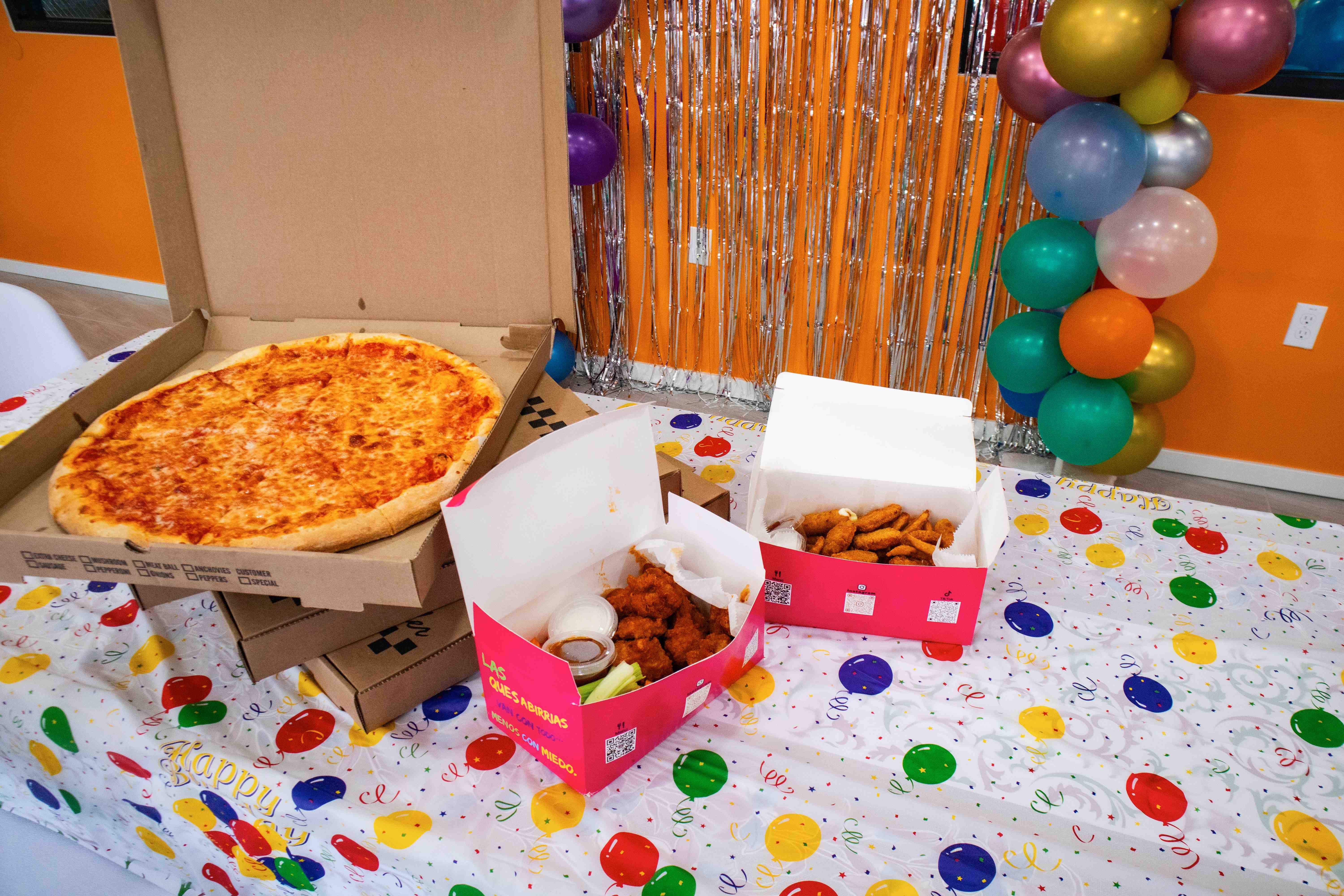 Party room decorated with balloons, silver streamers, and a food spread