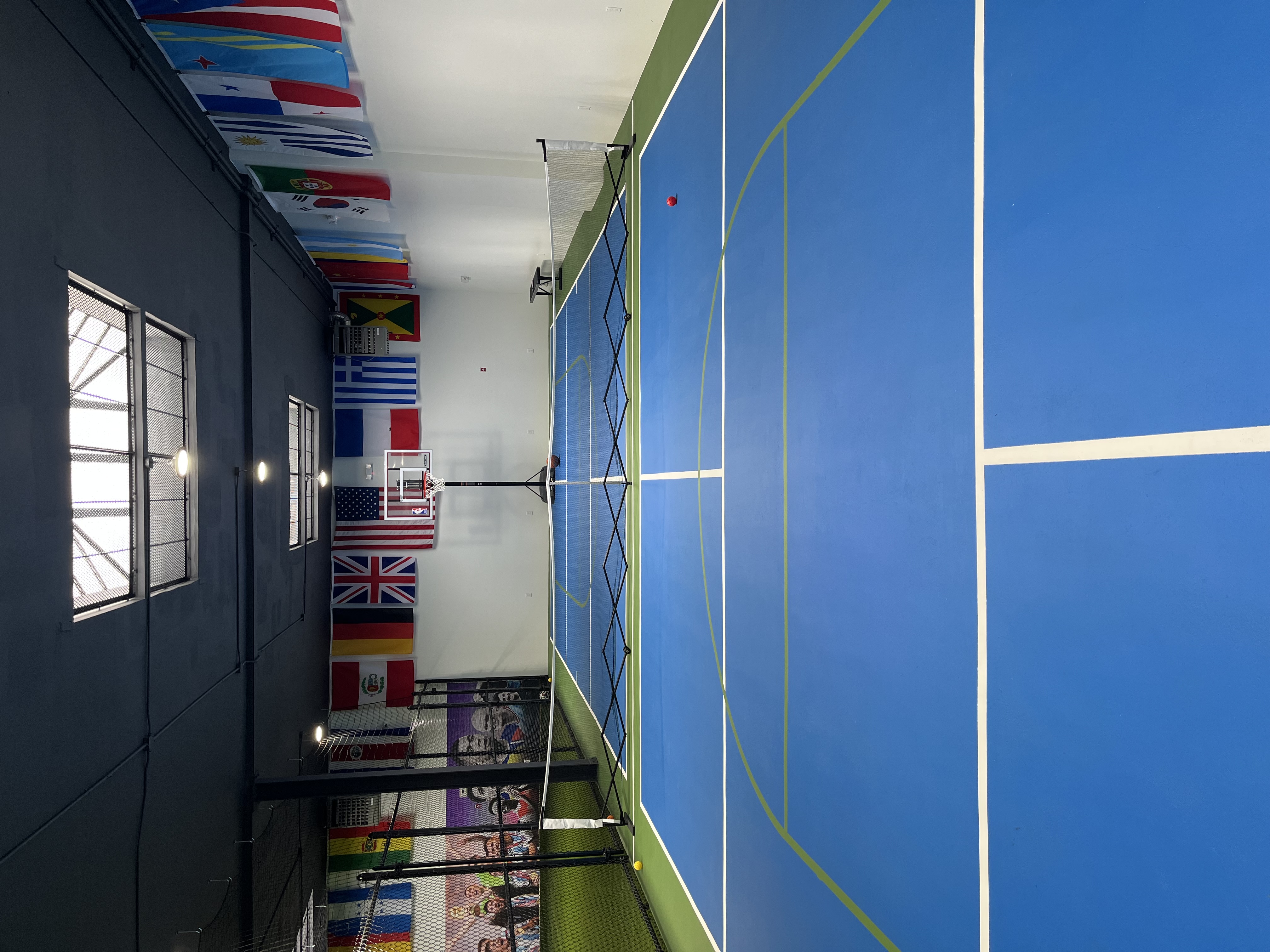 Pickleball court with blue surface, nets, and international flags